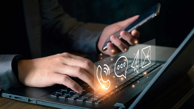 close up of a user interacting with a laptop and phone,overlayed with glowing digital icons respresenting customrer support channels
